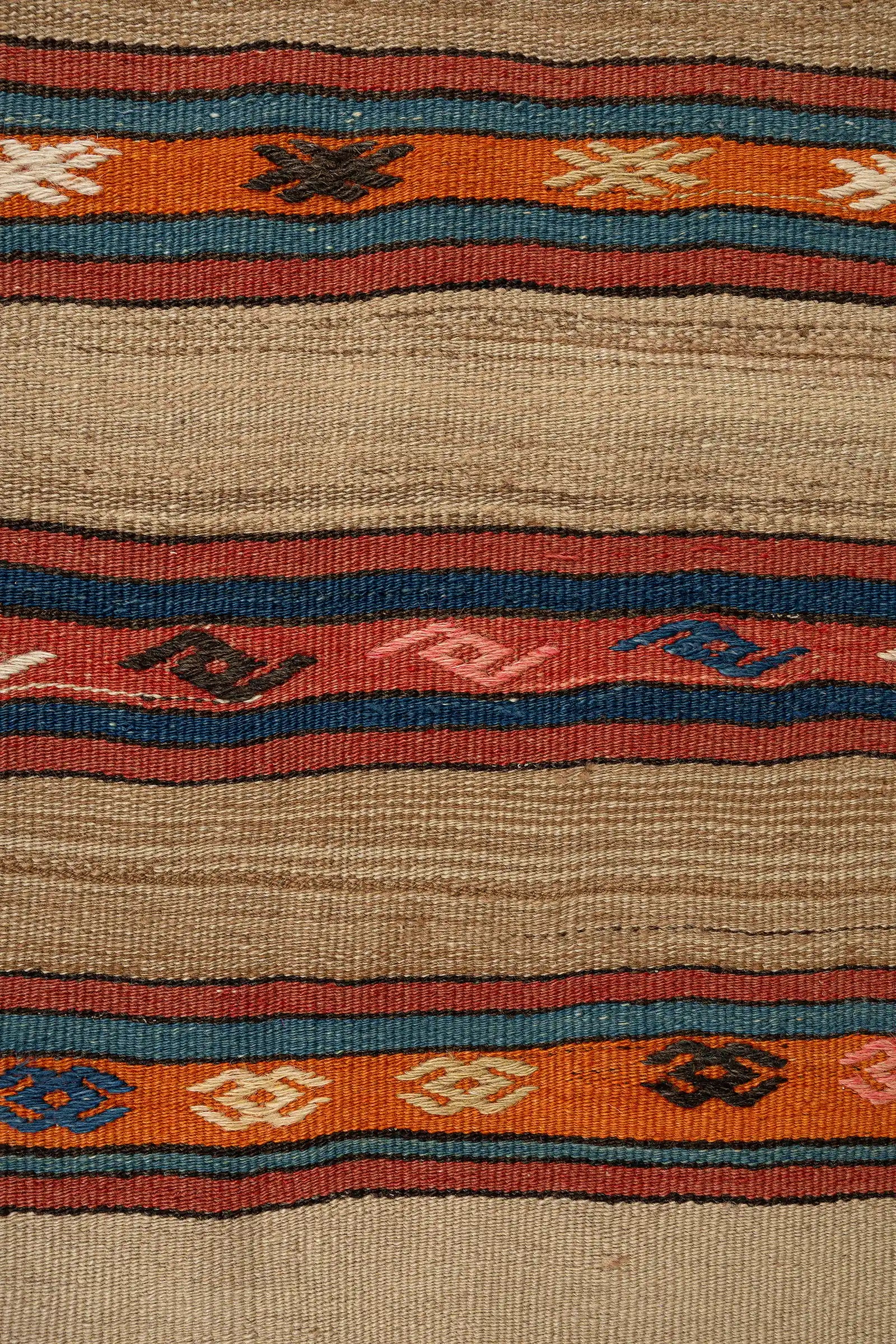 Detailaufnahme eines farbigen Zierstreifens – orangefarbener Streifen mit eingestreuten kleinen Symbolen in Weiß, Blau, Rosa, Schwarz und Gelb, gerahmt von blauen und roten Linien auf naturbraunem Grund