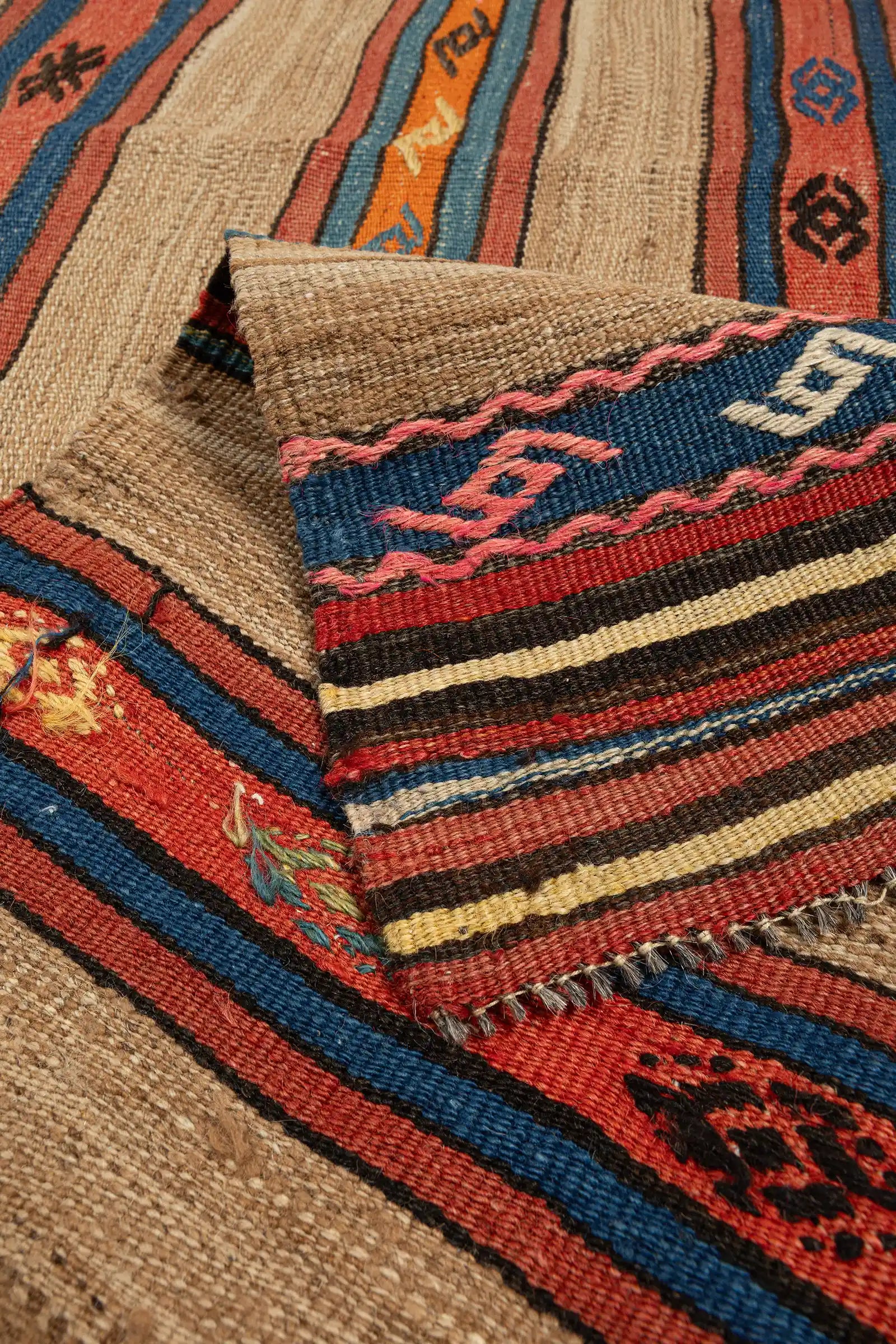 Vorder- und Rückseite im Vergleich – Ecke des Kelims umgeschlagen, Rückseite mit gestreiftem Musterbild, Fransenabschluss aus naturbelassener, heller Wolle mit zartem Zickzackrand