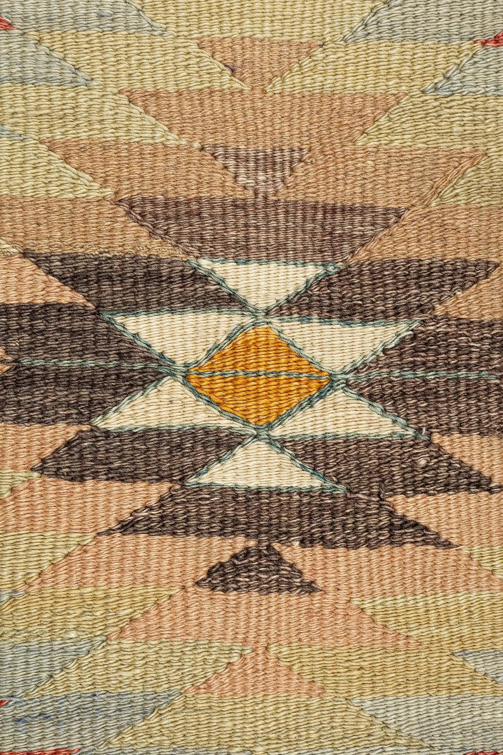 Detailaufnahme einer zentralen Raute – gezackte Farbverläufe in Türkis, Zimt und Sand mit innerem Medaillonmotiv