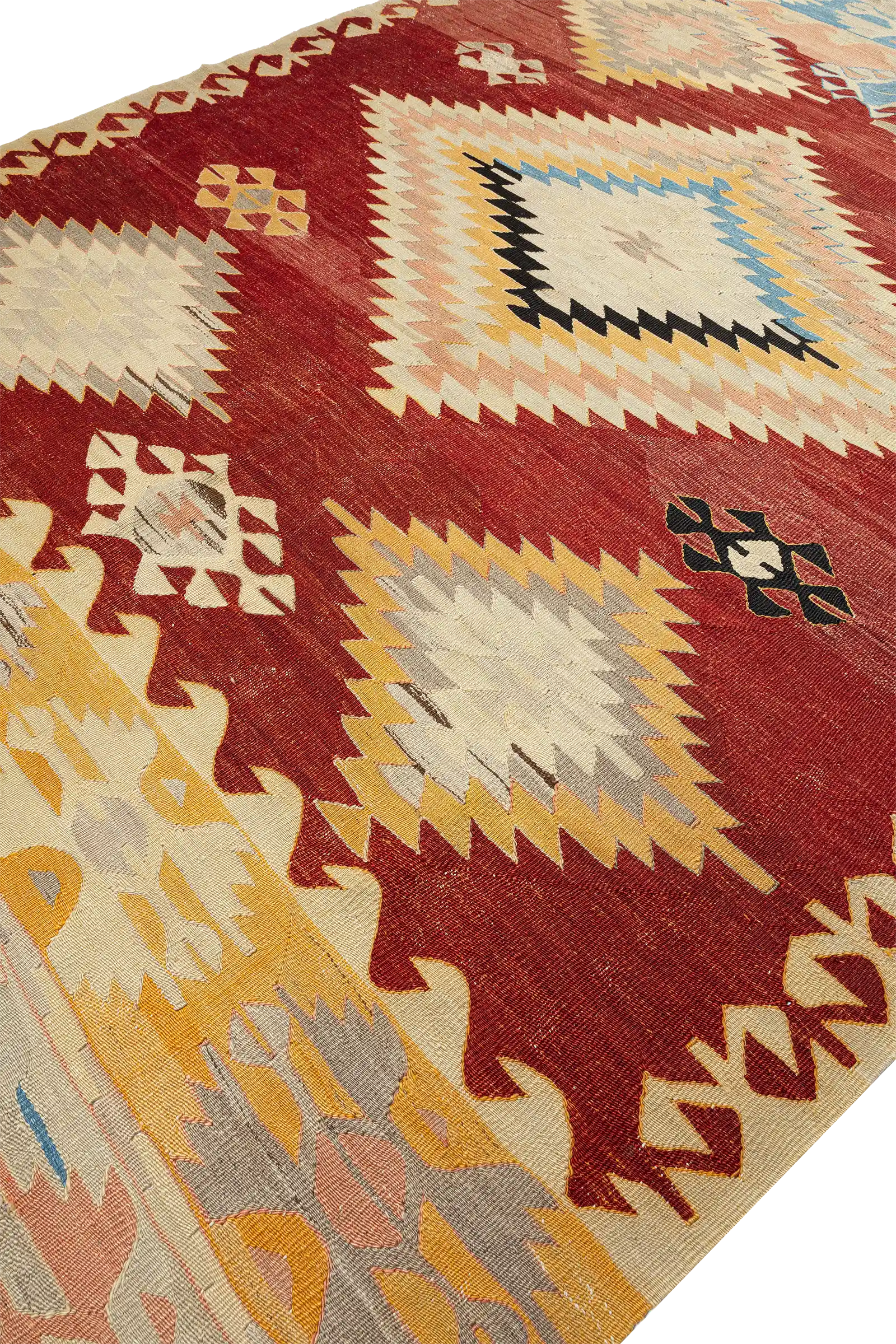Schräge Seitenansicht des Kelims – Fokus auf die gezackten Kanten der Raute und angrenzende Bordürenmotive, warmer Gesamteindruck durch gedeckte Gelb- und Erdtöne