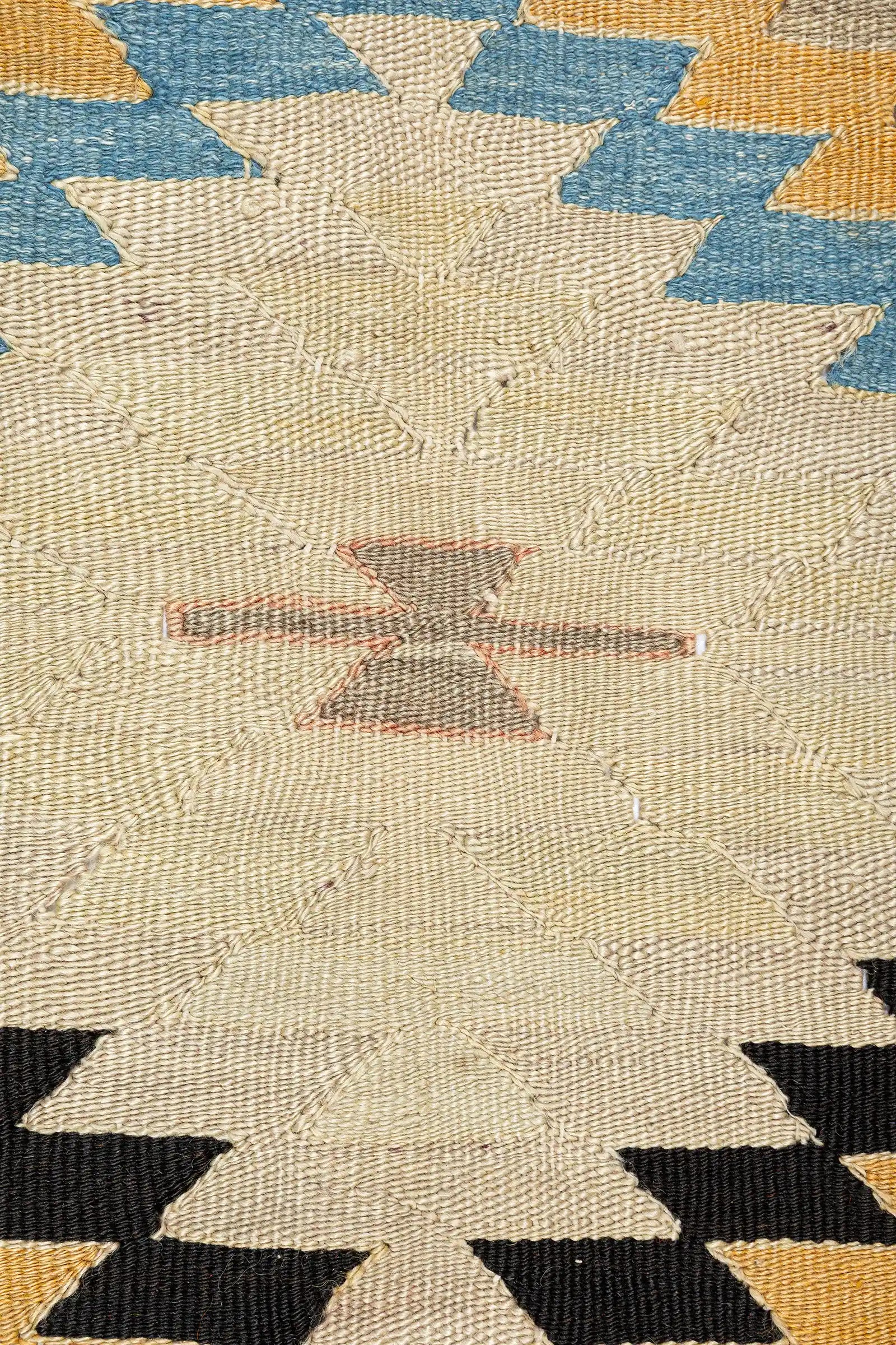 Detailaufnahme der Zackenraute – mehrstufige, helle Raute mit kräftiger Umrandung in Schwarz, Gelb, Blau und Weiß auf rötlich-braunem Grund, textile Struktur und Farbverläufe gut sichtbar