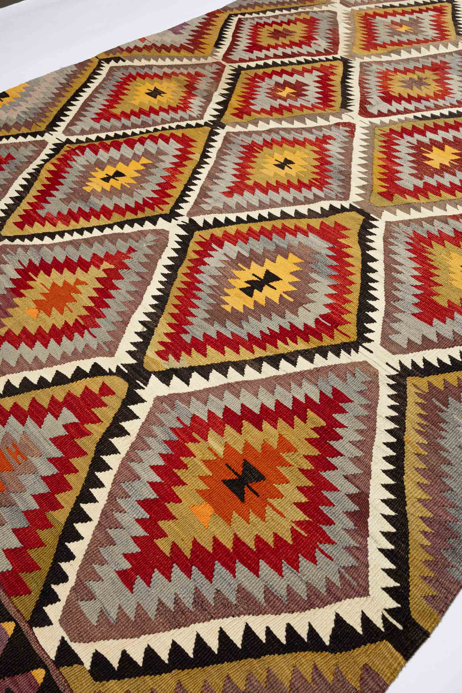 Schräger Blick auf das sich wiederholende Muster, bestehend aus rot-gelben Rauten mit dunklem Zentrum und mehrfarbiger Kontur.