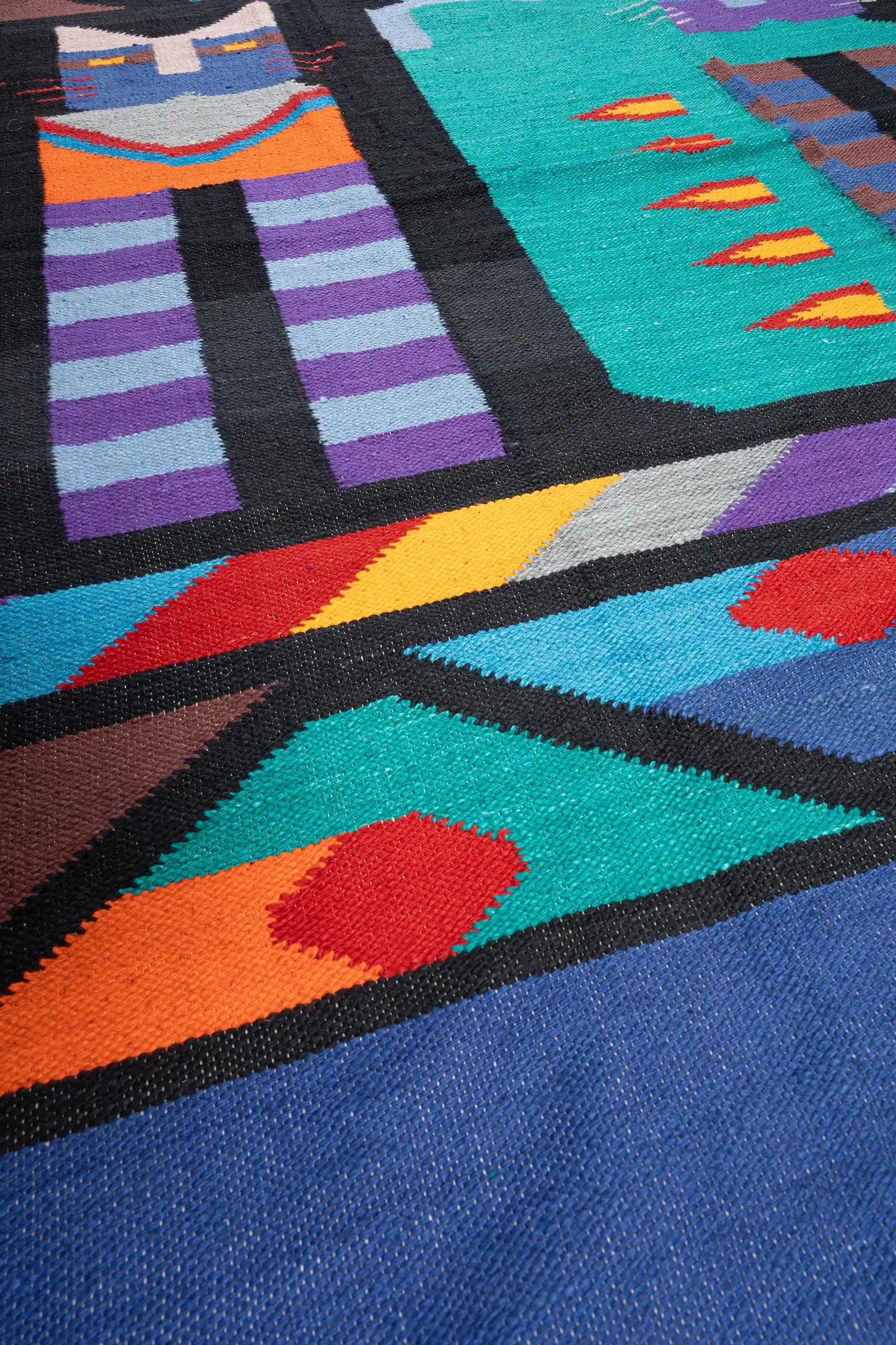 Feine Webstruktur mit glattem Finish, klare Farbflächen in Türkis, Orange und Rot mit scharfen Kontrasten entlang der Umrisslinien.