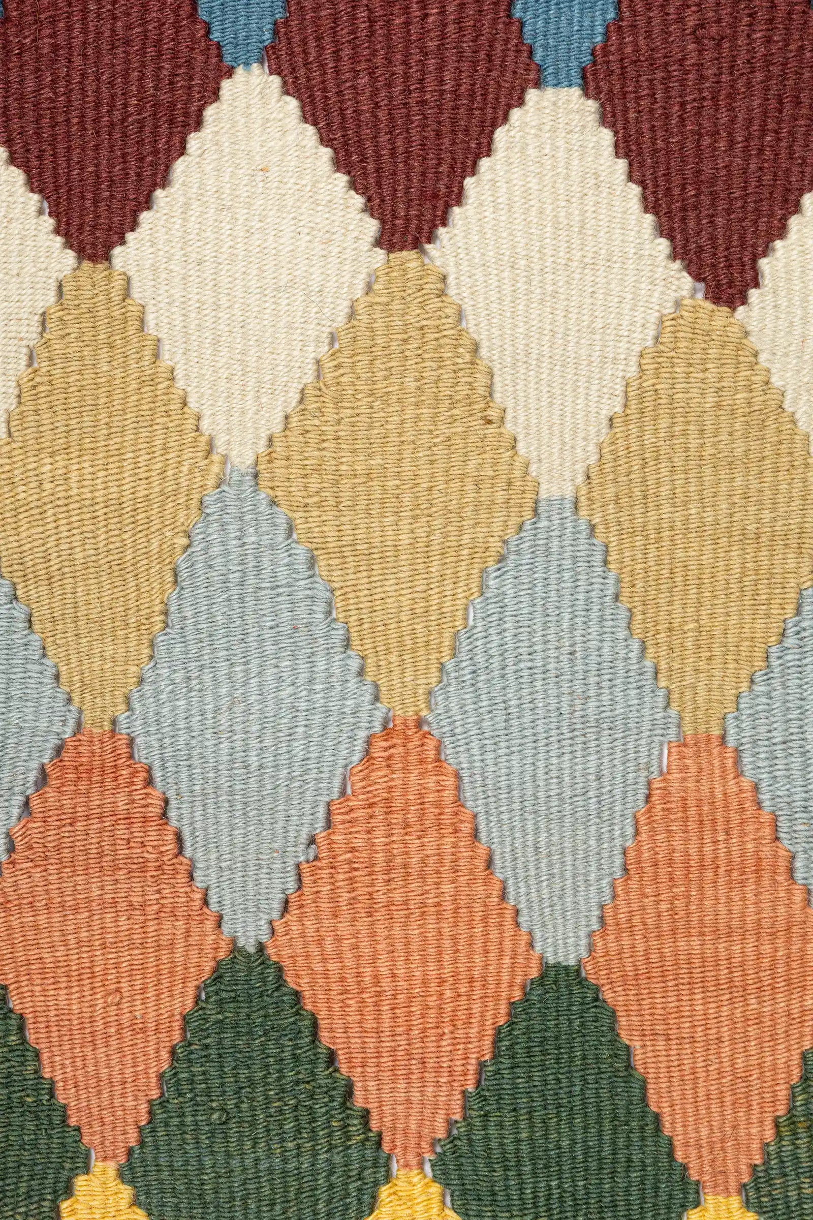 Detailaufnahme des zentralen Bereichs – präzise gewebte Rautenform mit klar abgegrenzten Farbfeldern. Zu sehen sind kleinformatige Farbflächen in kräftigem Kontrast, sauber eingefasst durch die umliegende Struktur. Die Webung ist dicht und gleichmäßig.