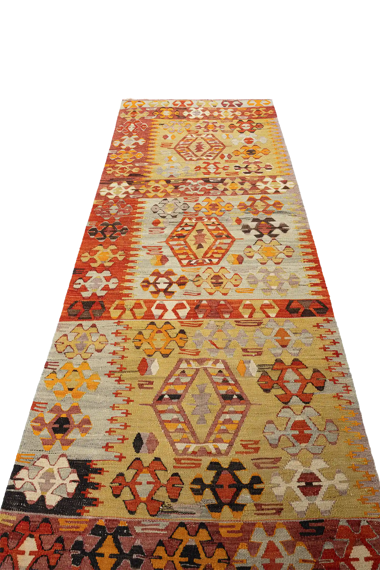 Seitlich aufgenommener Blick auf die Teppichfläche mit deutlicher Sicht auf das mittlere Medaillon, flankiert von leuchtend rot-orangefarbenen Symbolen auf beigem Grund mit fließendem Farbübergang.