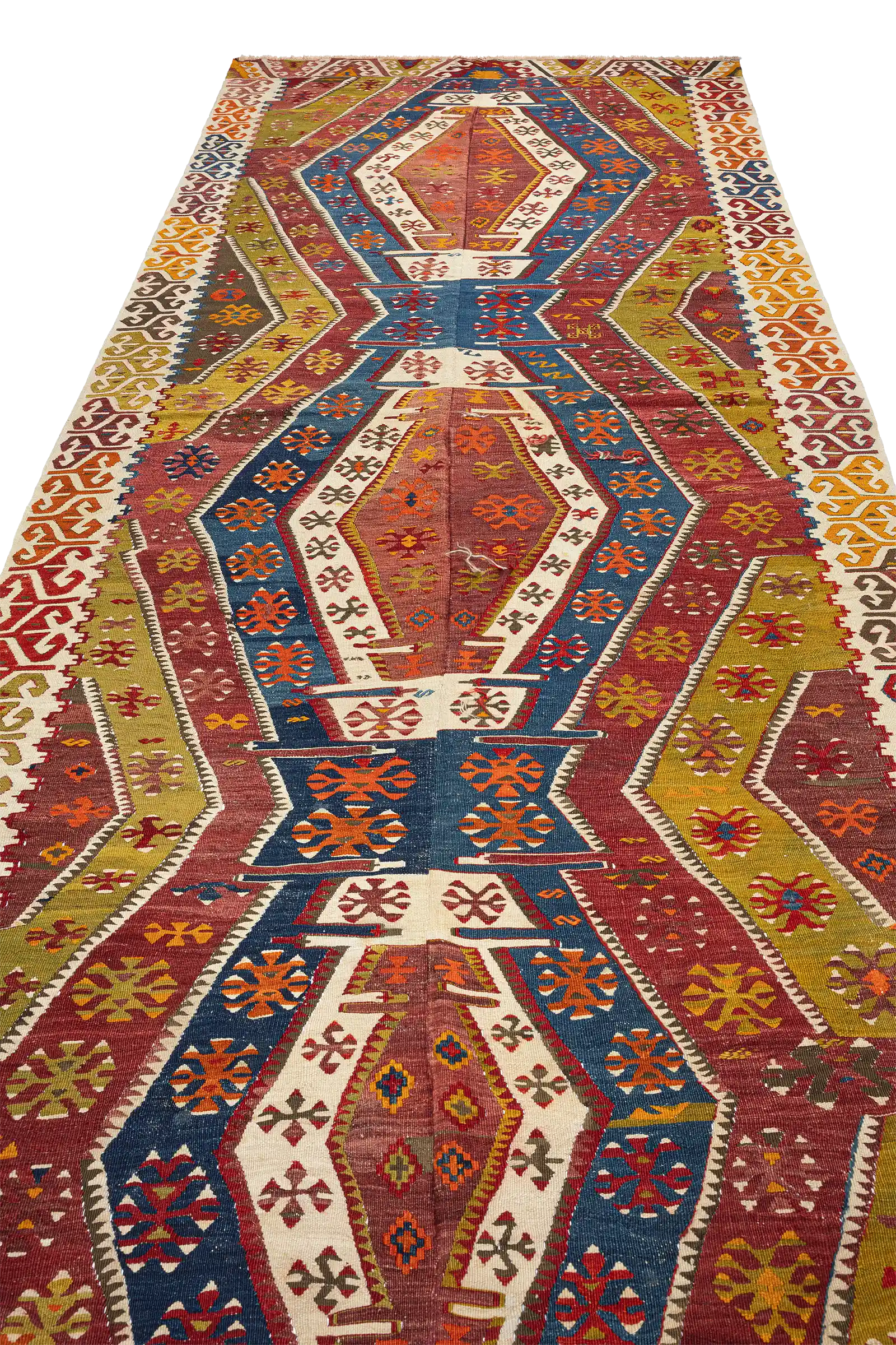 Seitlich aufgenommene Gesamtfläche des Kelims mit klarer Tiefenwirkung; farbige Bahnen in Blau, Rot, Grün und Beige verlaufen diagonal zur Bildkante.