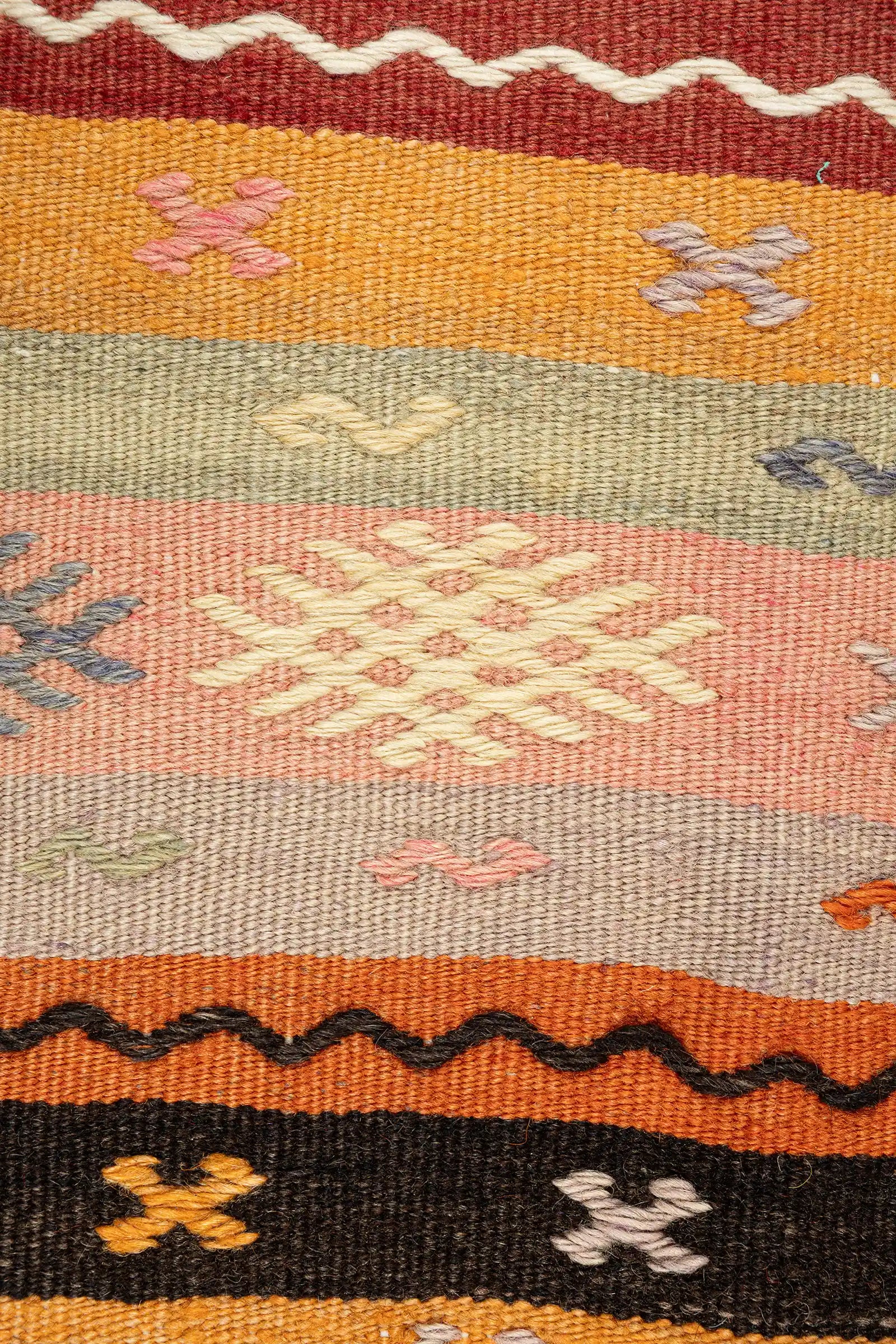 Detailaufnahme der eingewebten Formen – feine Stickstruktur mit kleinen, kreuzartigen und versetzten Elementen in kontrastreichen Garnfarben