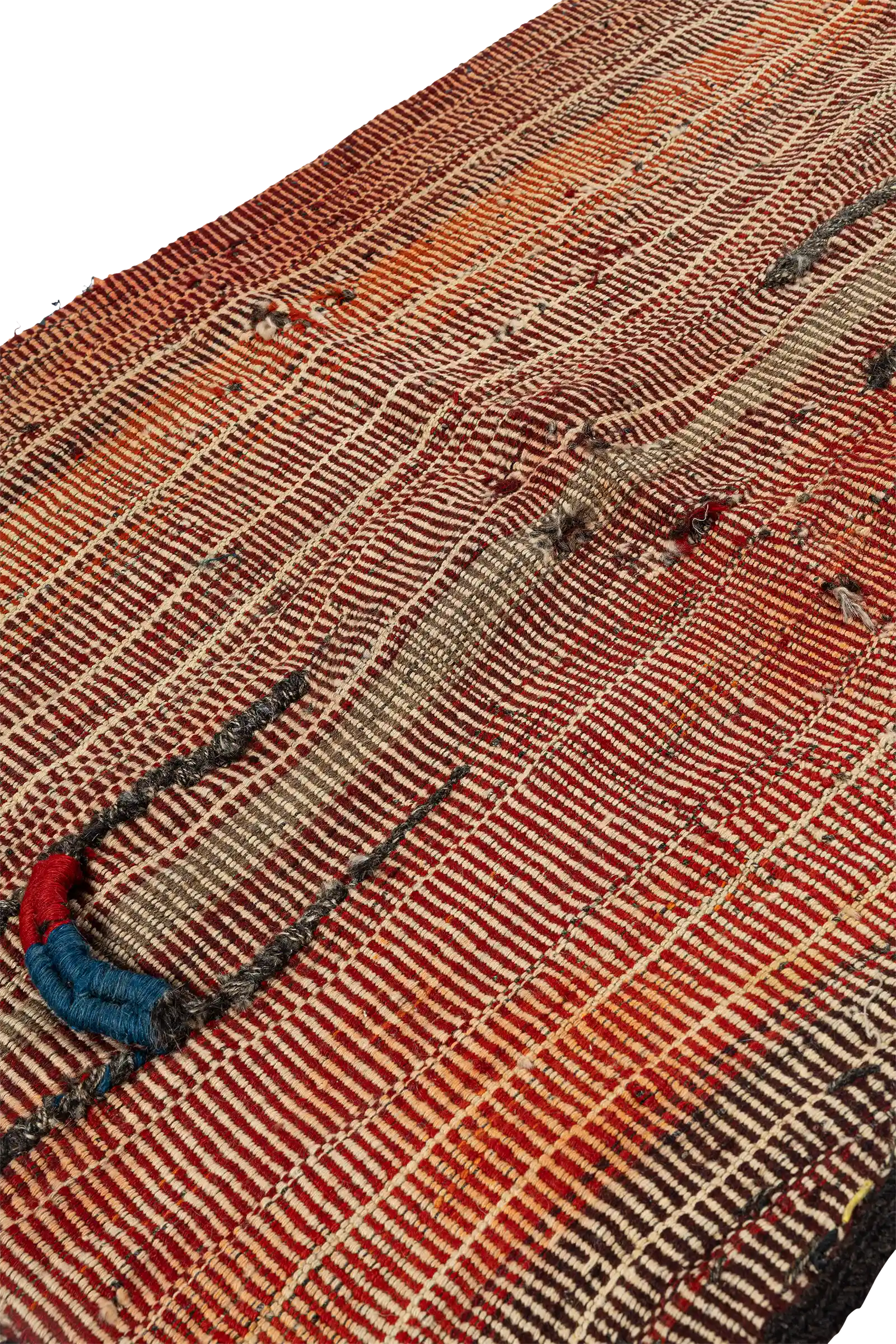Seitlich aufgenommene Fläche des Kelims mit betonten Weblinien in rostrotem Verlauf. Sichtbar sind aufgesetzte Details in Schwarz sowie eine gewölbte Oberfläche mit leichten Wellen.