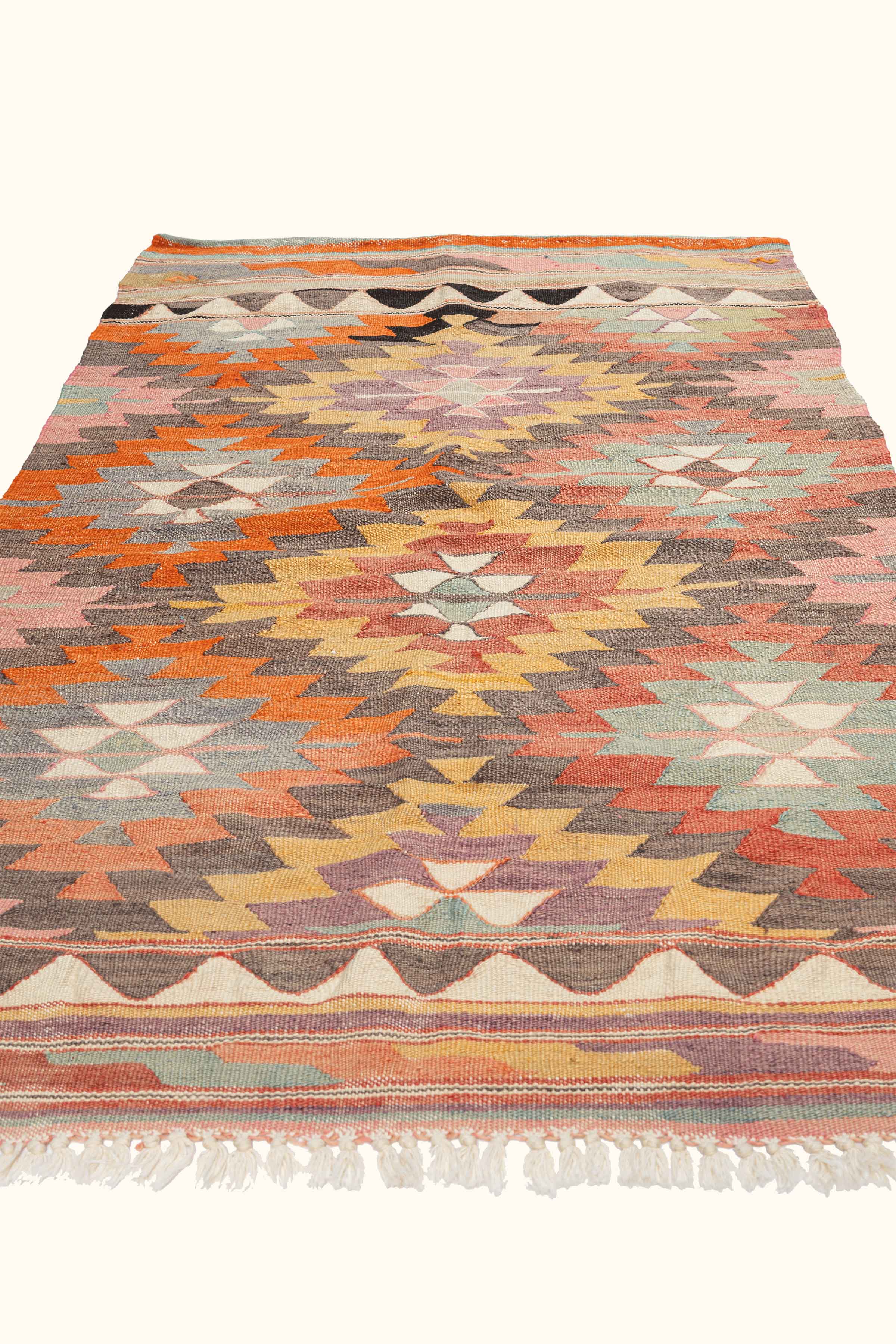 Schräge Perspektive auf den Kelim mit Zickzack-Muster und eingewebten Symbolen wie Yıldız und Göz