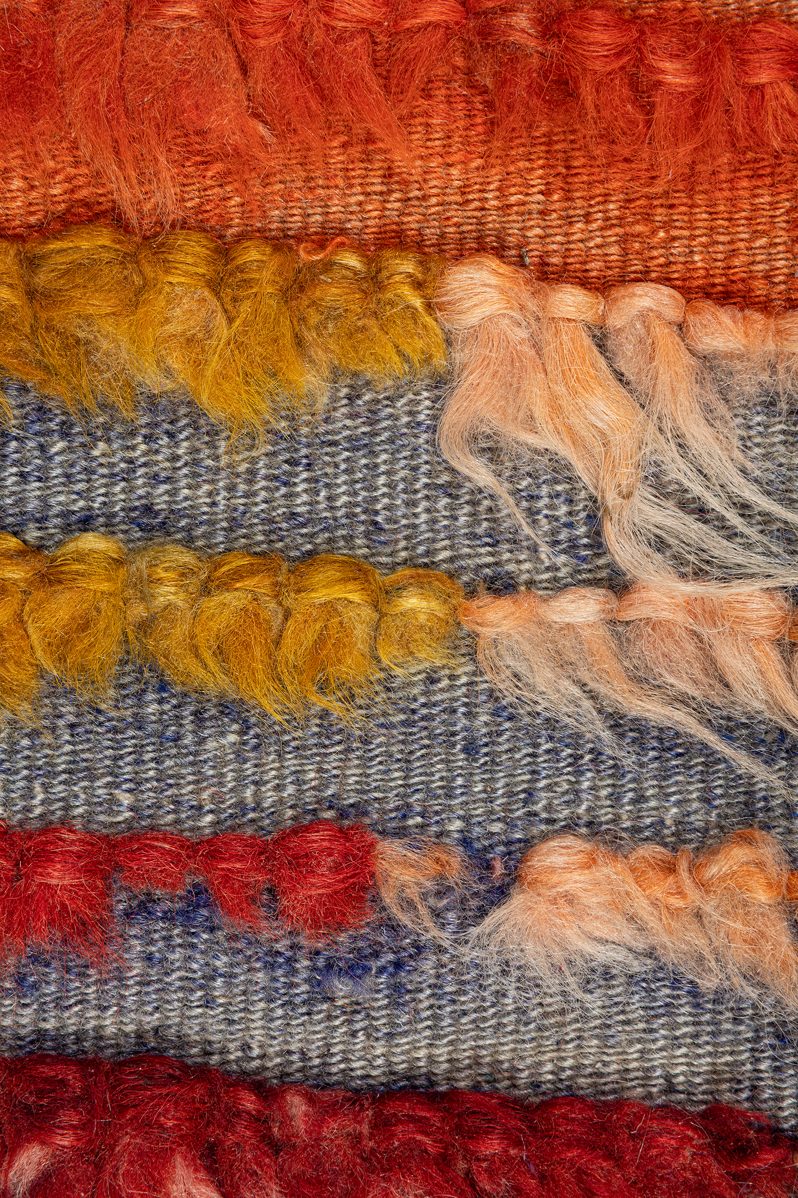 Nahaufnahme der flauschigen, roten und schwarzen Wollfasern im unteren Bereich des Kilims, mit sichtbaren dichten Knoten.