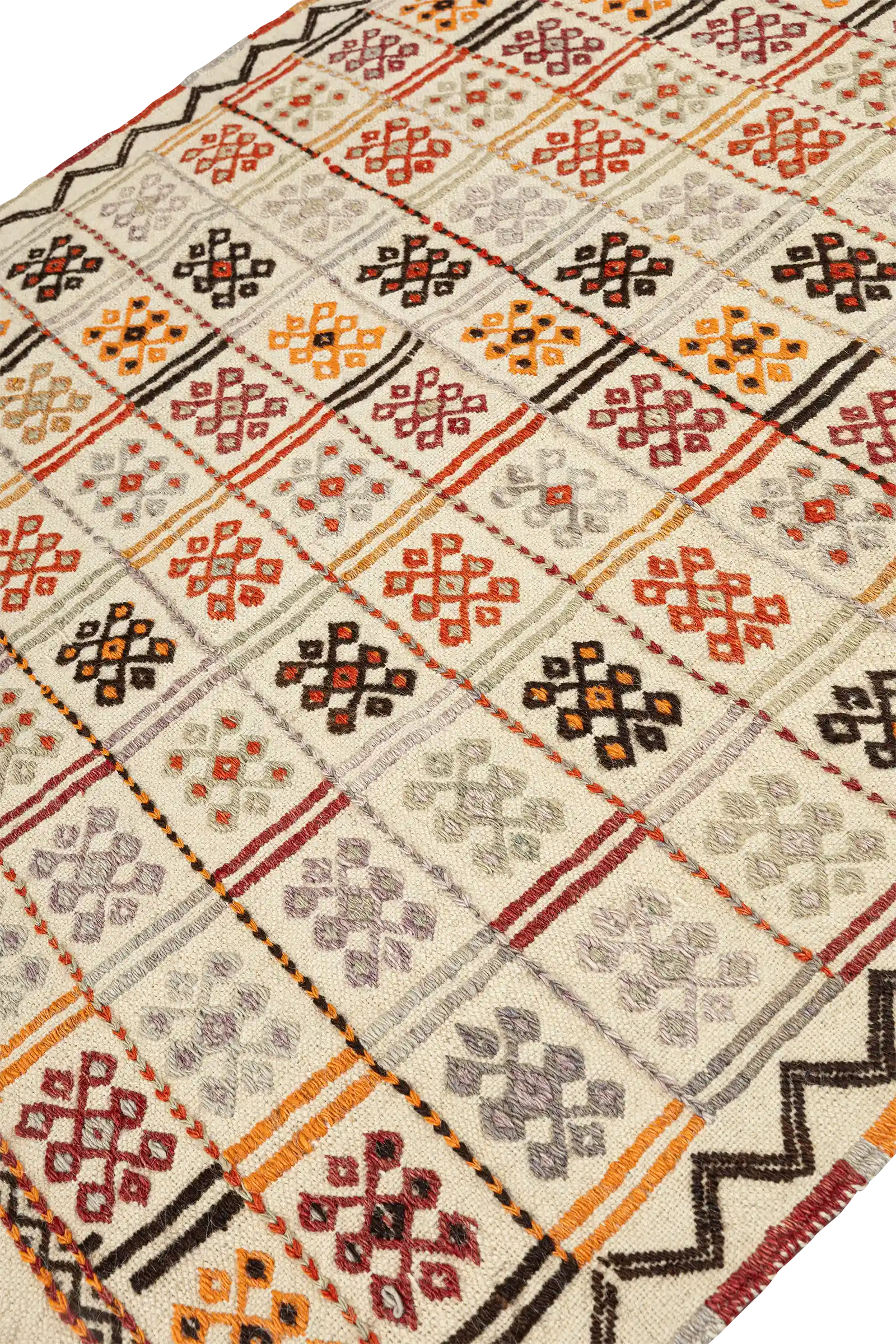 Ansicht entlang des Kilims mit Fokus auf die regelmäßige Anordnung der quadratischen Muster, eingefasst von farblich abgesetzten Linien und Zickzackrand auf cremefarbenem Hintergrund.