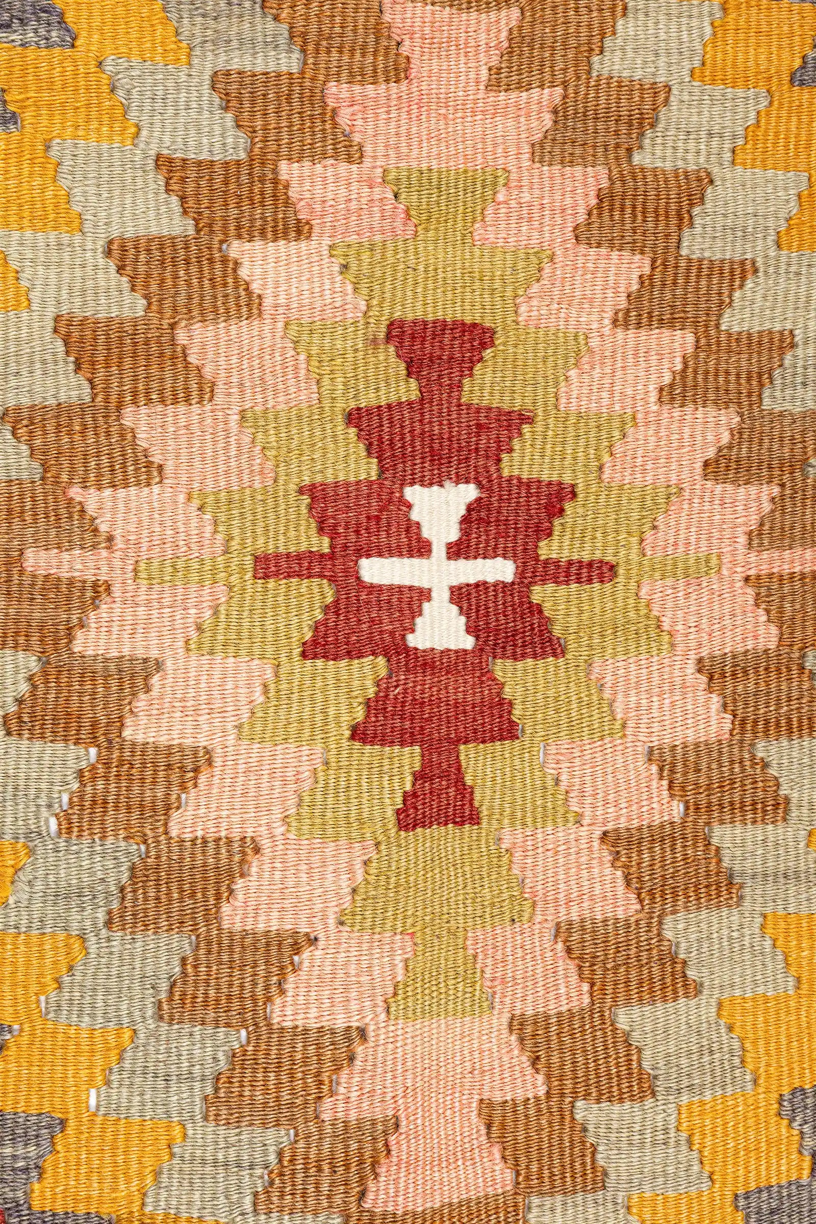 Detailaufnahme des zentralen Rautenmotivs – eng gestufte Zickzack-Kanten in Rosé, Senfgelb, Olivgrün und Ziegelrot auf heller Basis