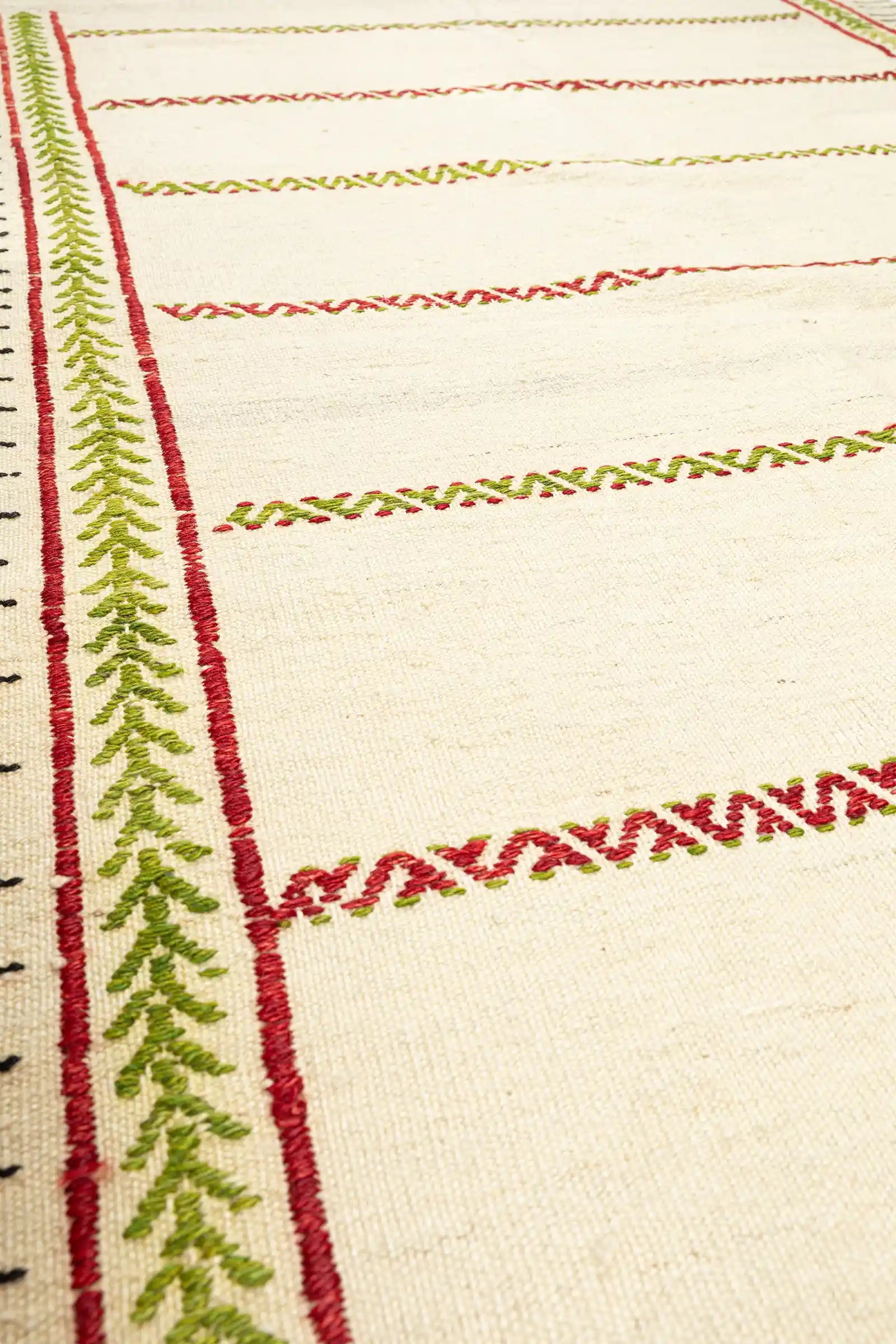 Nahaufnahme der Textur – fein und dicht gewebte Wollstruktur mit gleichmäßiger Oberfläche, Stickelemente leicht erhaben