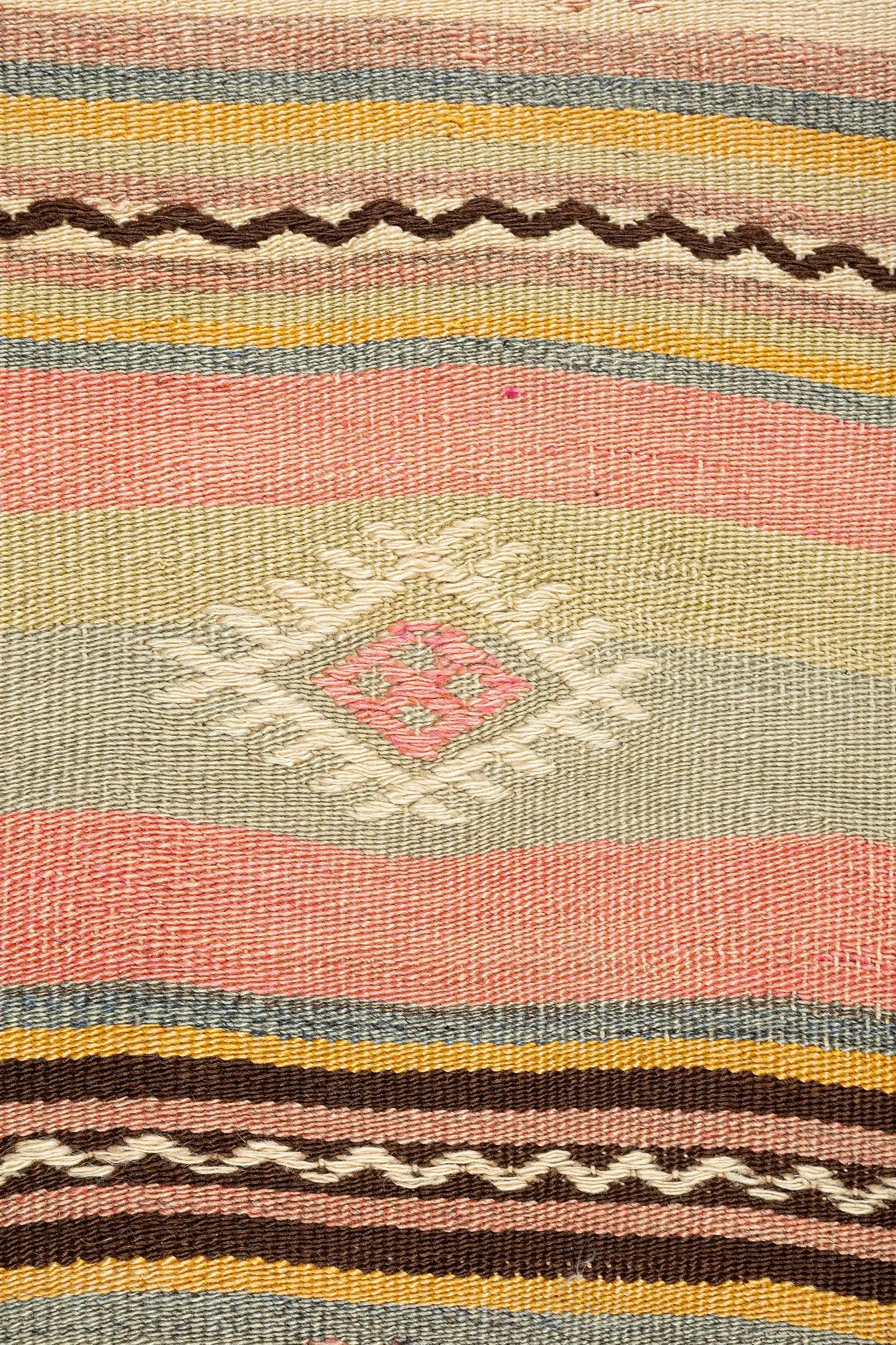 Nahaufnahme eines Cicim-Symbols – gesticktes Rautenmuster in Altweiß und Rosa auf lachsfarbener Grundfläche