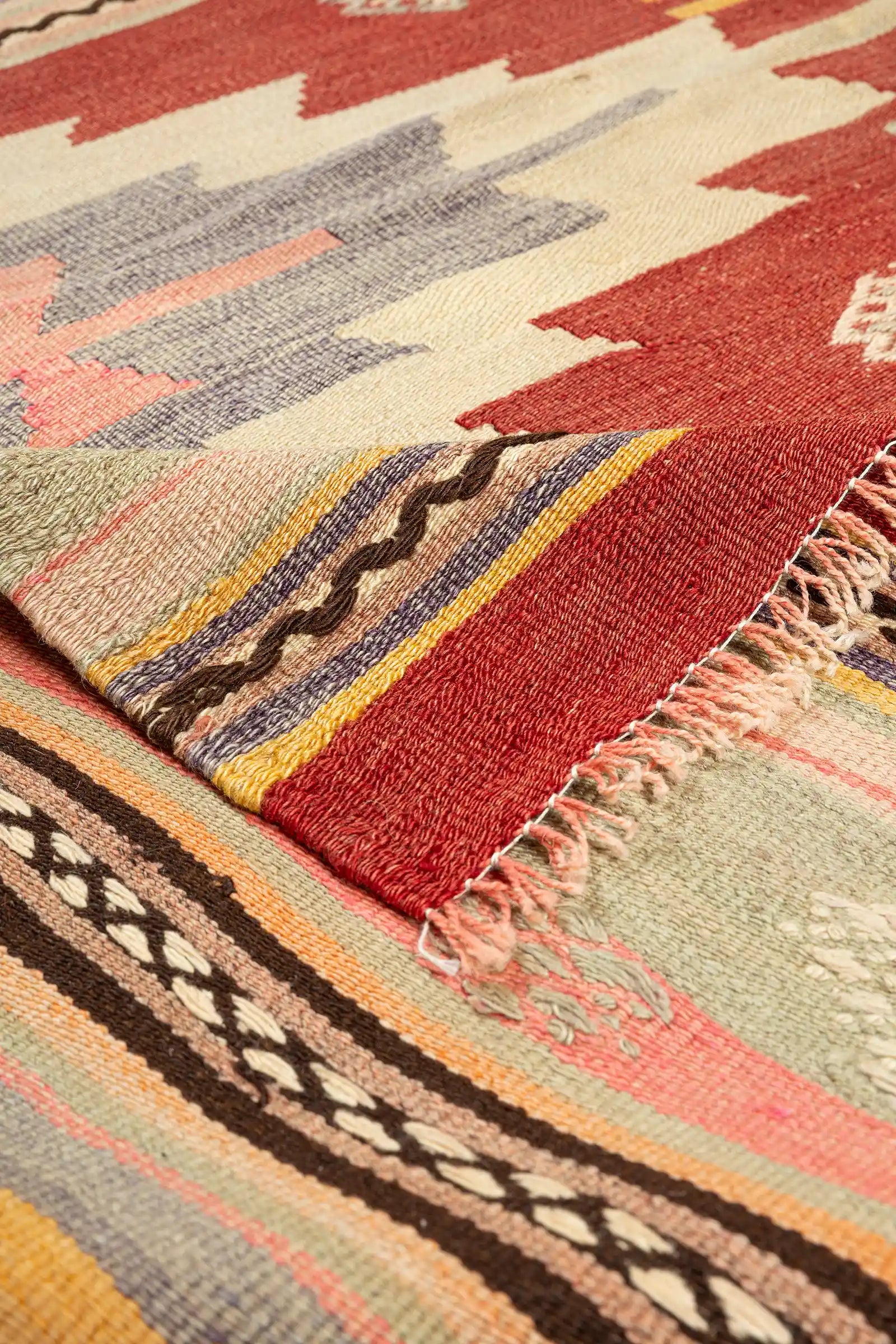Umgeschlagene Ecke des Kelims – handgewebter Abschluss mit Fransen und Rückseite sichtbar