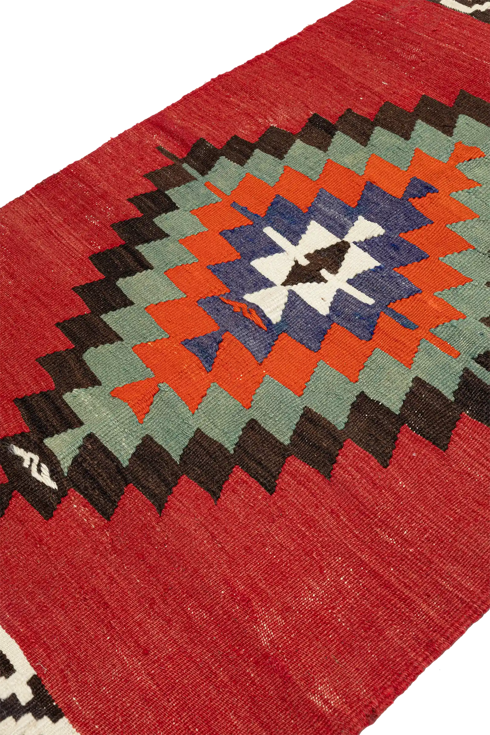 Schräge Seitenansicht – das abgestufte Zackenmotiv entfaltet sich konzentrisch aus der Mitte, auf rotem Hintergrund mit leichter Patina