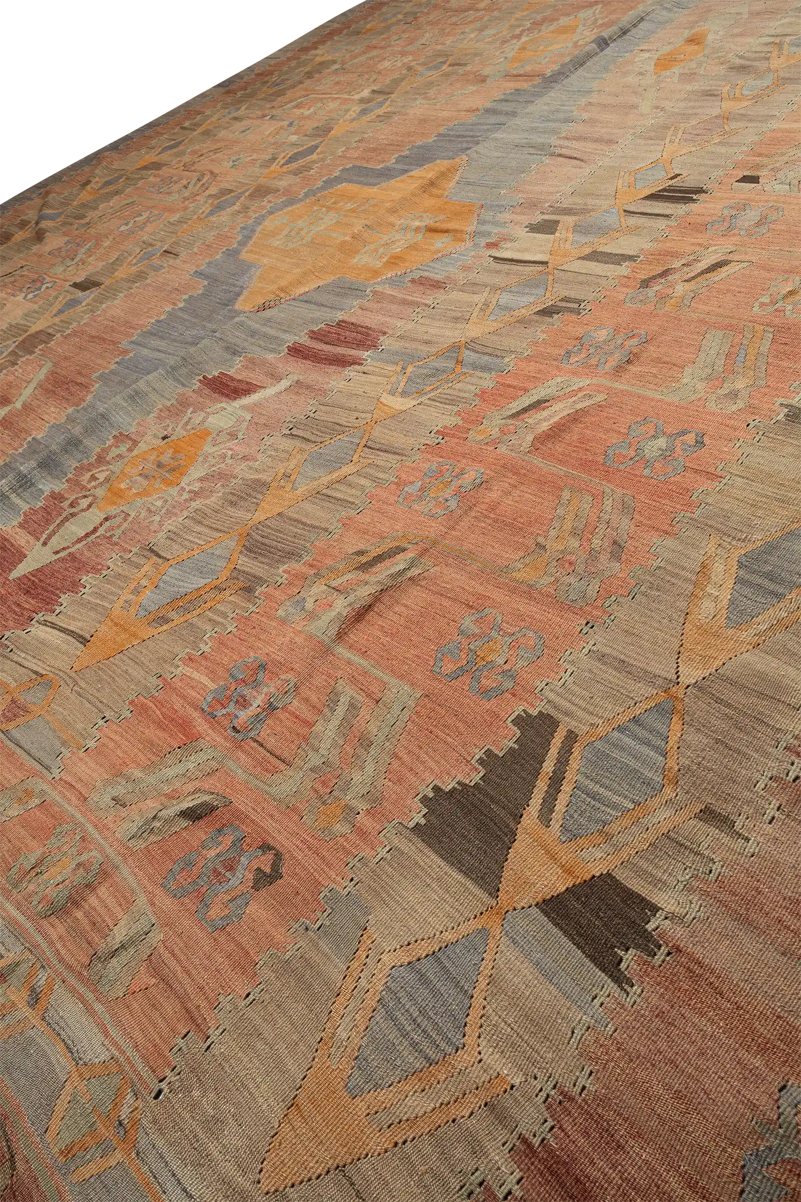 Seitlich geneigte Aufnahme mit Fokus auf die textilen Strukturen und wiederholten Ornamentformen in verblasstem Rosa, Beige, Graugrün und Blaugrau auf gleichmäßig gewebtem Grund.