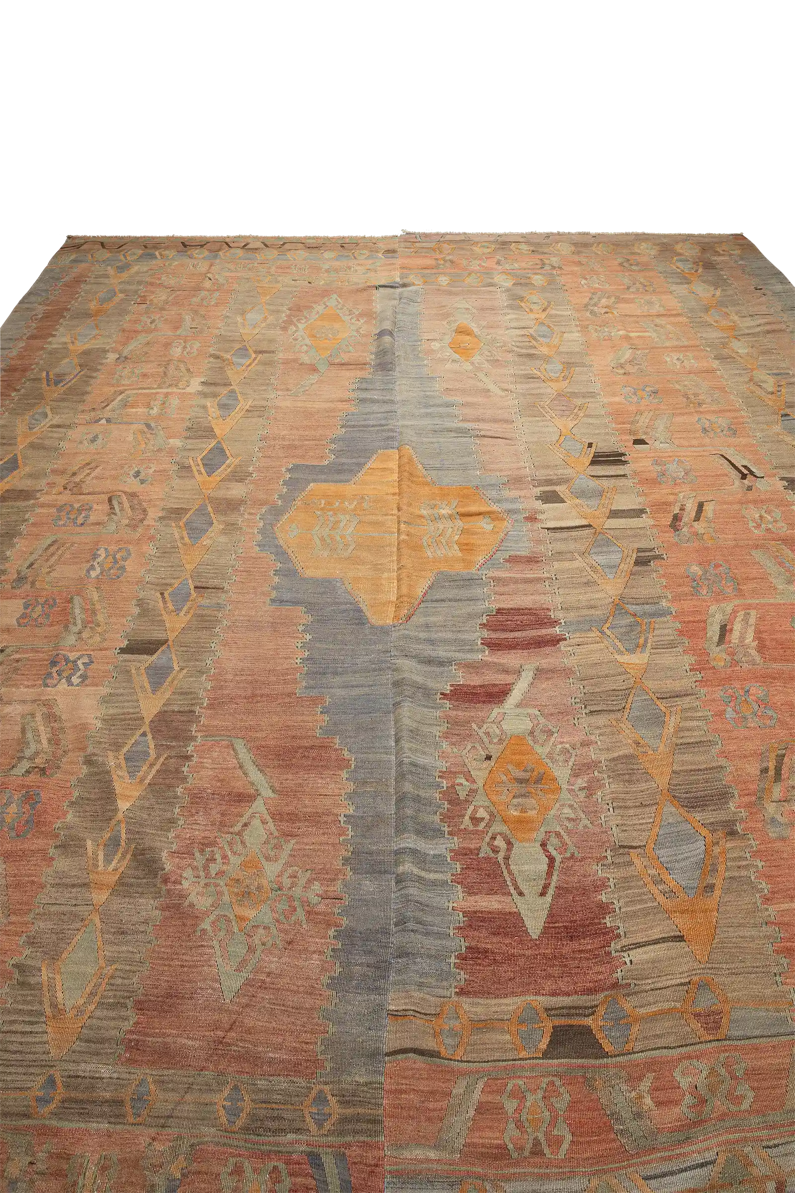 Schräger Blick über die Teppichfläche, zeigt die zentrale Mittelachse mit großem rautenförmigem Medaillon in Ocker und Blaugrau, flankiert von Reihen kleinerer Motive in hellem Rosa, Beige, Graublau und Braun.