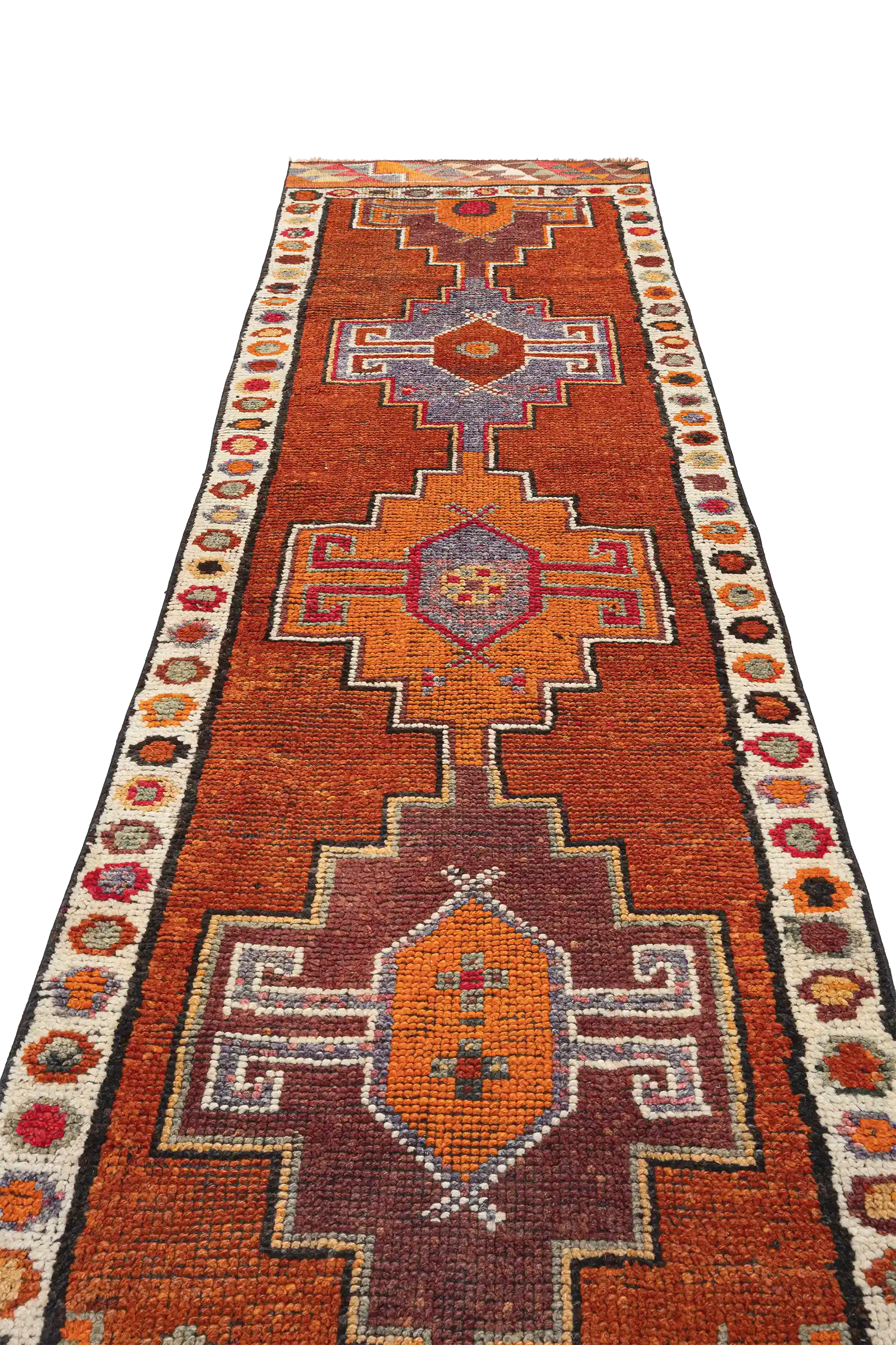 Schräger Blick entlang der Längsachse des Teppichs, zeigt mehrere mittige Medaillons in verschiedenen Farben, umgeben von kräftigem Rot und kontrastierendem, detailreichem Rand mit bunten Blüten- oder Kreisformen.