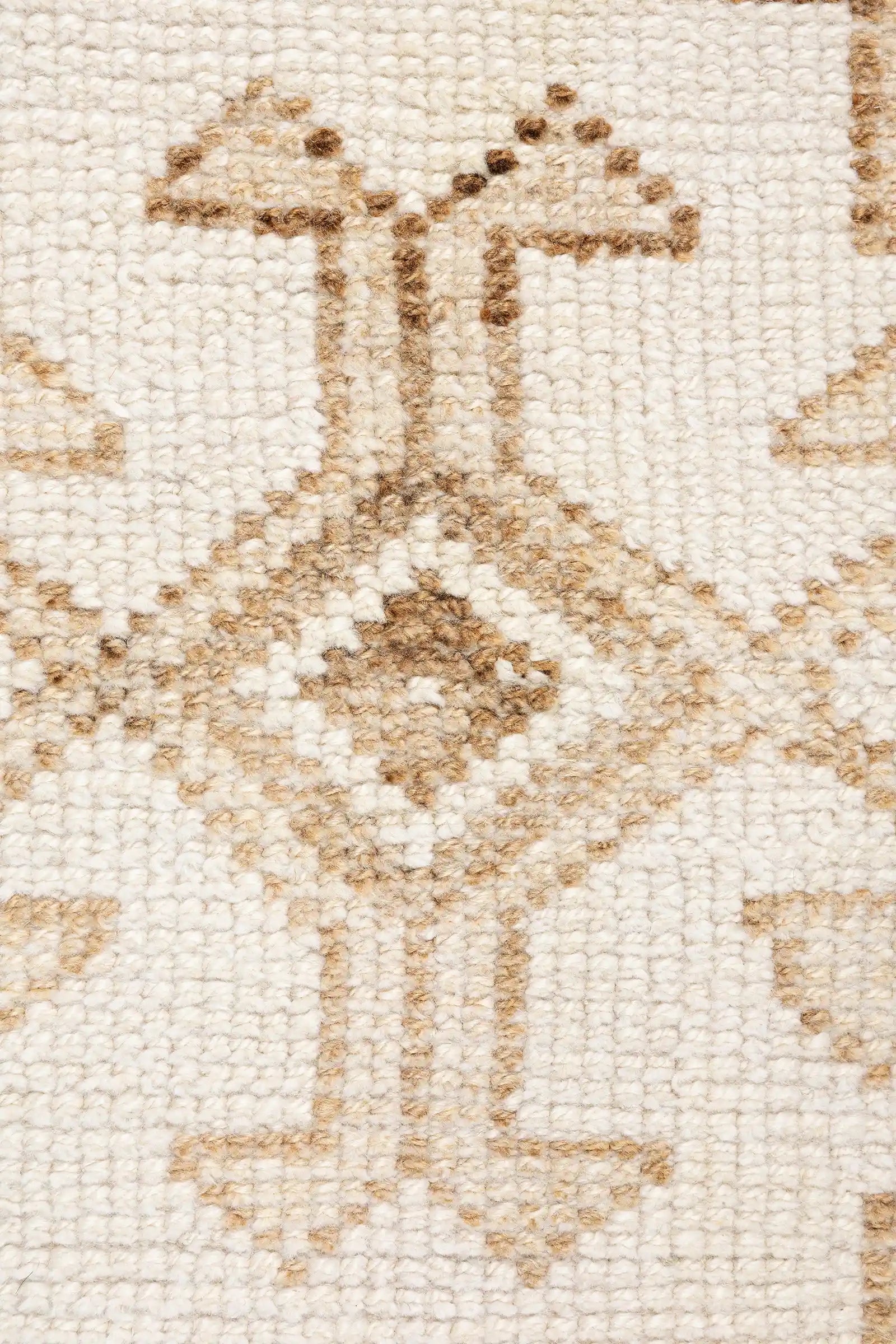 Nahaufnahme eines Motivbereichs mit symmetrisch aufgebautem Rauten- und Linienmuster in warmem Beige und Hellbraun auf naturfarbenem Hintergrund, mit klarer Sicht auf die feine Wollstruktur.