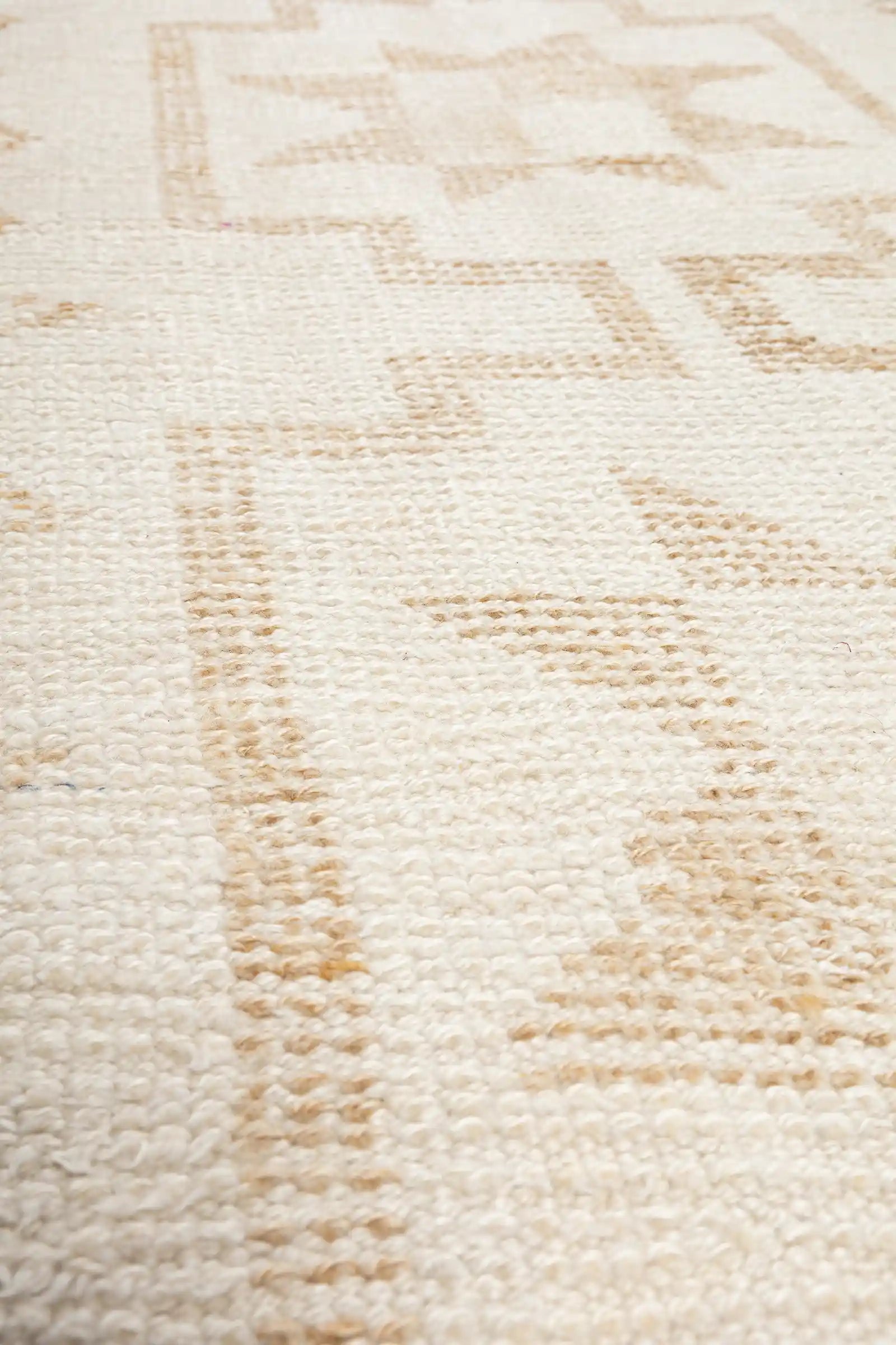 Extremer Zoom auf die Webstruktur mit gleichmäßigen, dicken Wollfasern in Creme und hellem Beige, die die minimalen Farbabstufungen des Musters zeigen.