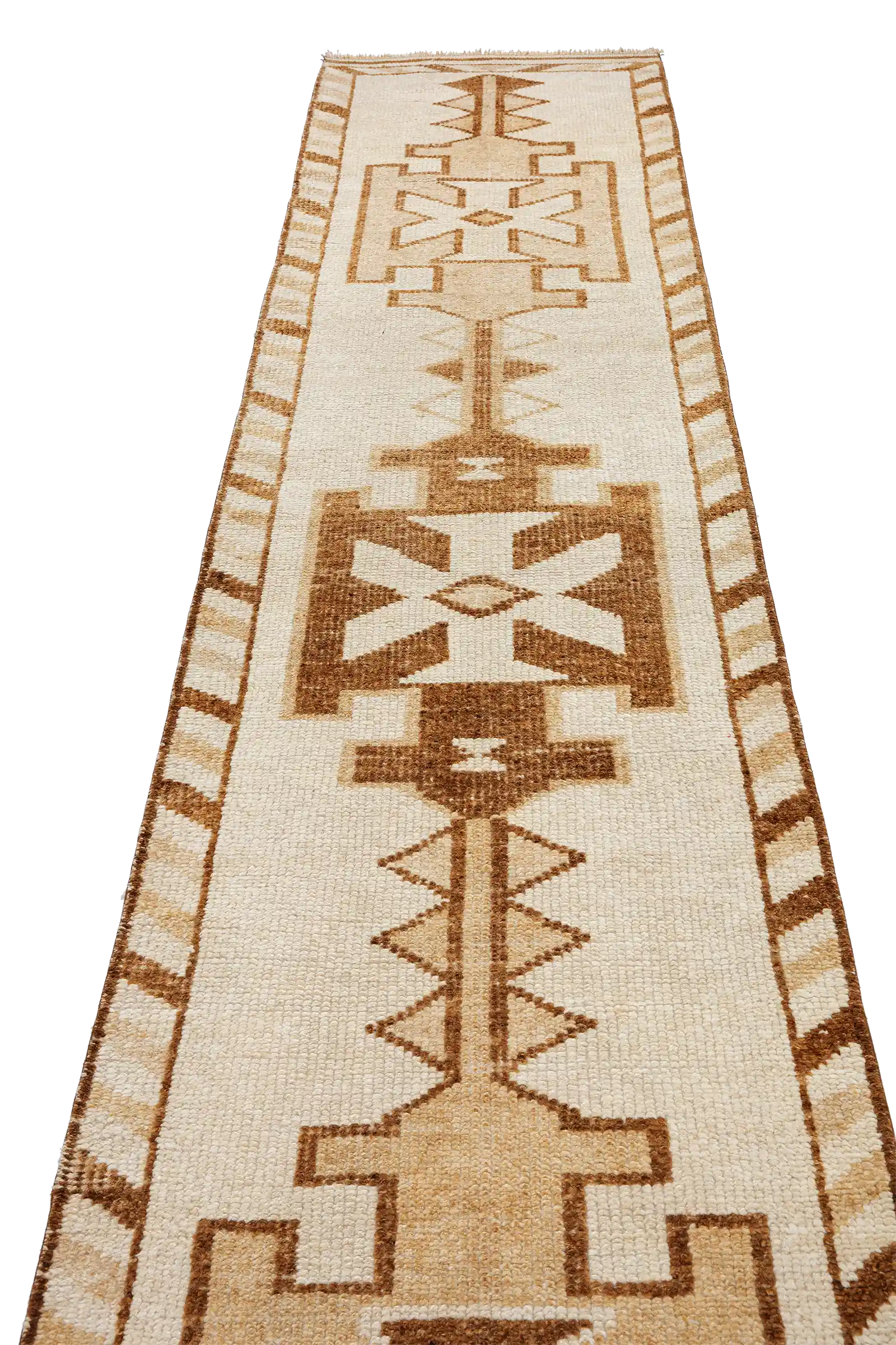 Schräg aufgenommene Ansicht entlang der Längsachse des Teppichs mit wiederkehrenden symmetrischen Ornamenten in beigen und braunen Tönen auf hellem Grund.