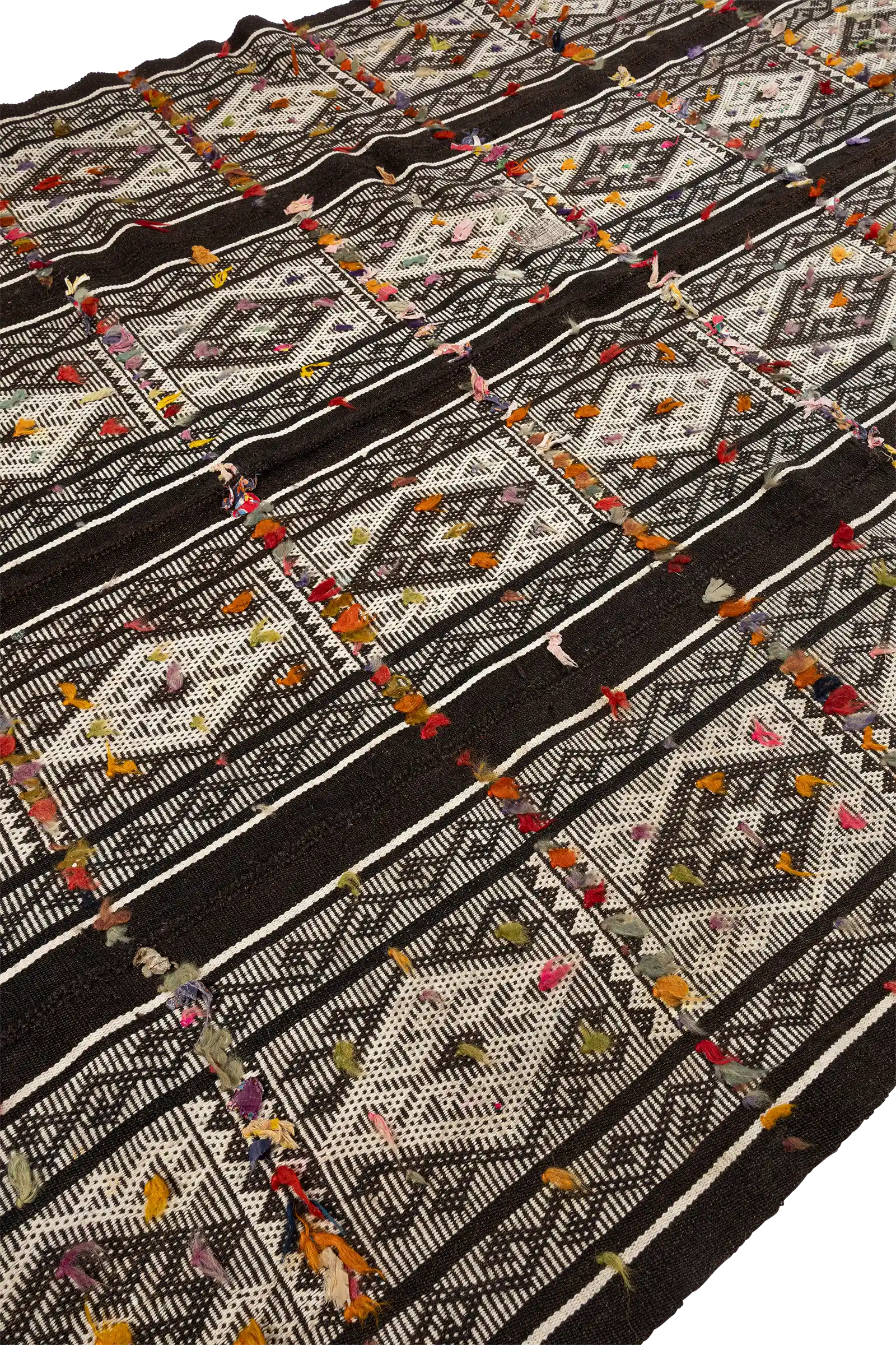 Schräg fotografierter Ausschnitt des Kilims mit gut erkennbaren horizontalen Streifen, klaren Rautenmustern und farbigen Garnknoten, die in regelmäßigen Abständen eingeknüpft sind