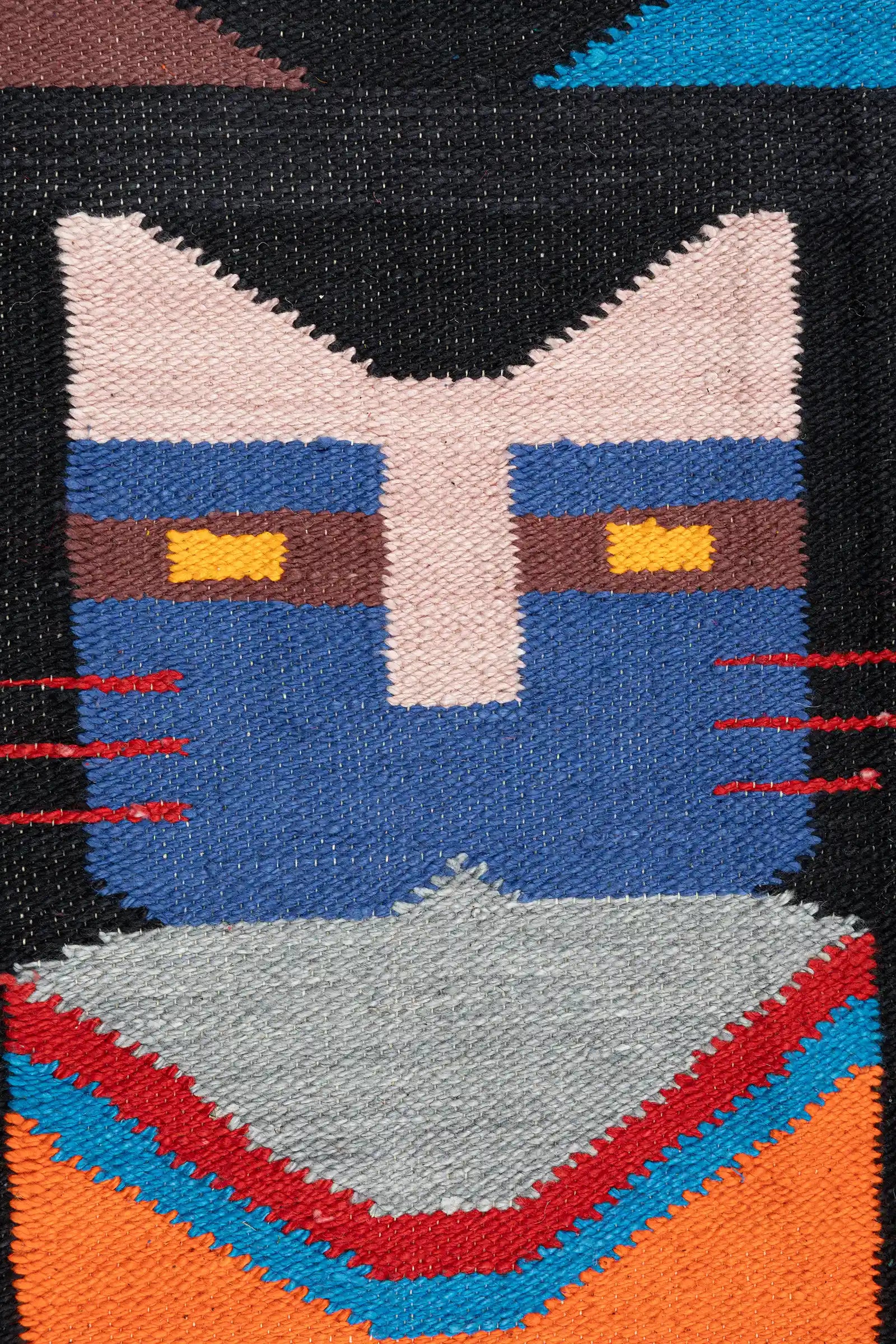 Nahaufnahme einer geometrischen Katzenfigur mit lilafarbenem Gesicht, gelben Augen und gestreiften Beinen in Lila- und Blautönen.