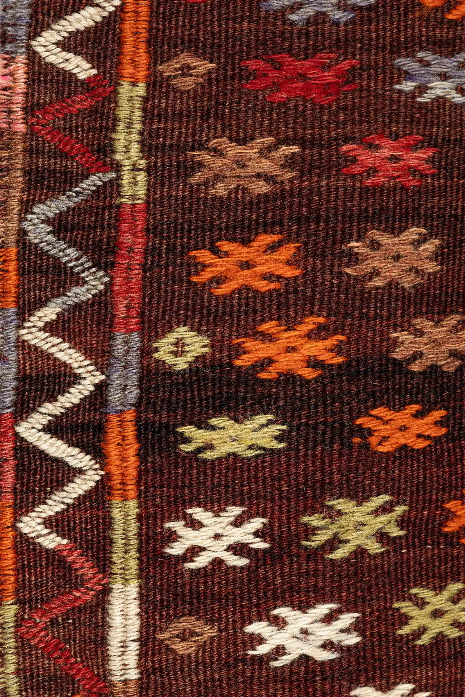 Detailaufnahme der kleinen Musterformen – fein eingewobene geometrische Elemente auf braunem Fond mit leichten Garnkontrasten