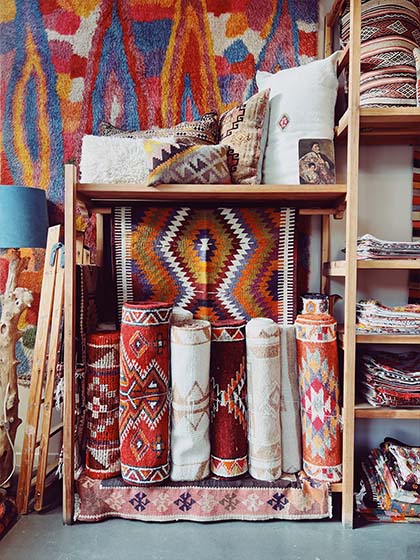 Holzregal, in dem viele bunte anatolische Kelims und Vintage Kelim Kissen ausgestellt sind